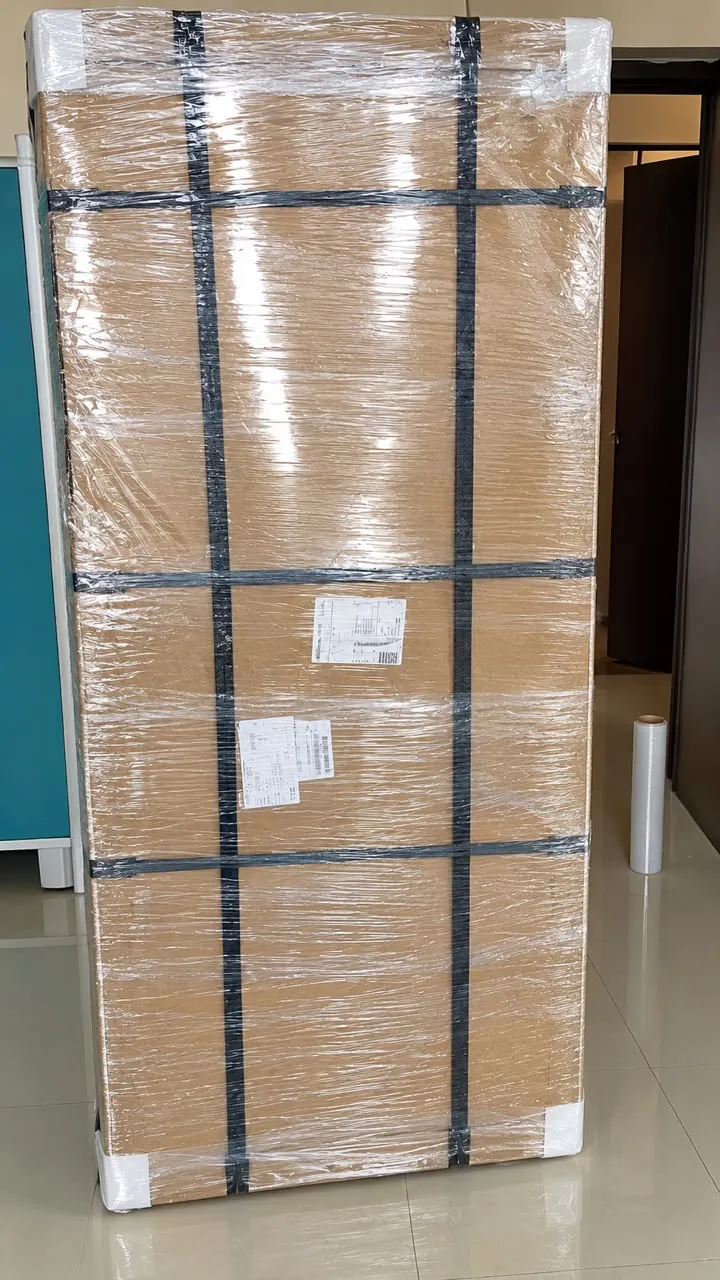 Tall wardrobe packed in cardboard, stretch film and corner guards, secured with black straps